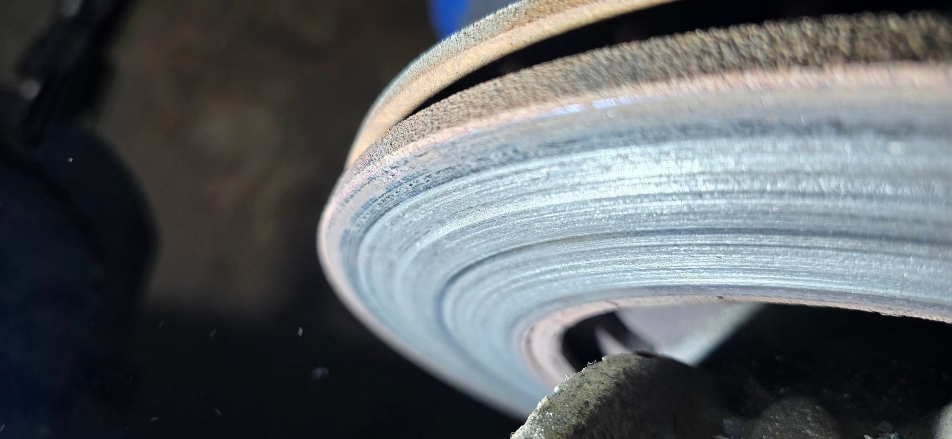 Close-up of a circular grinding wheel spinning against a metal surface, creating a blurred blue-gray edge.