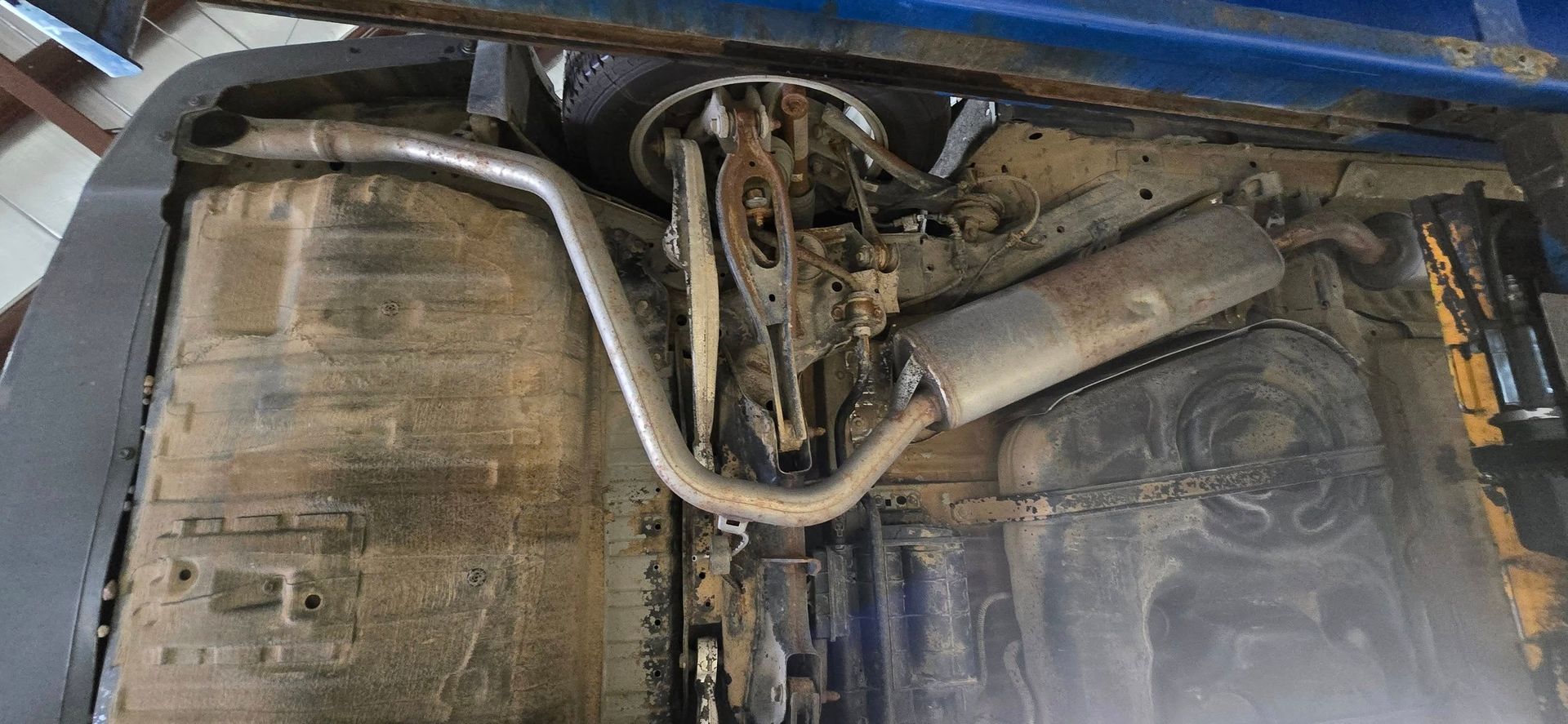 Dirty car engine bay with exposed hoses and parts, viewed from above