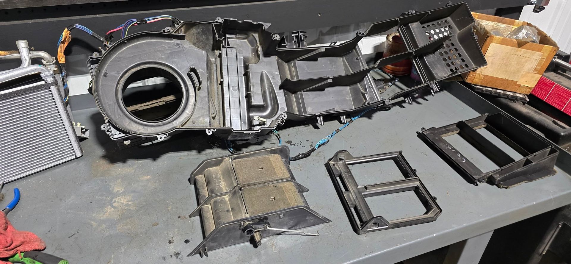 Disassembled sci-fi prop parts laid out on a workbench, including a circular gray device and black frame pieces.