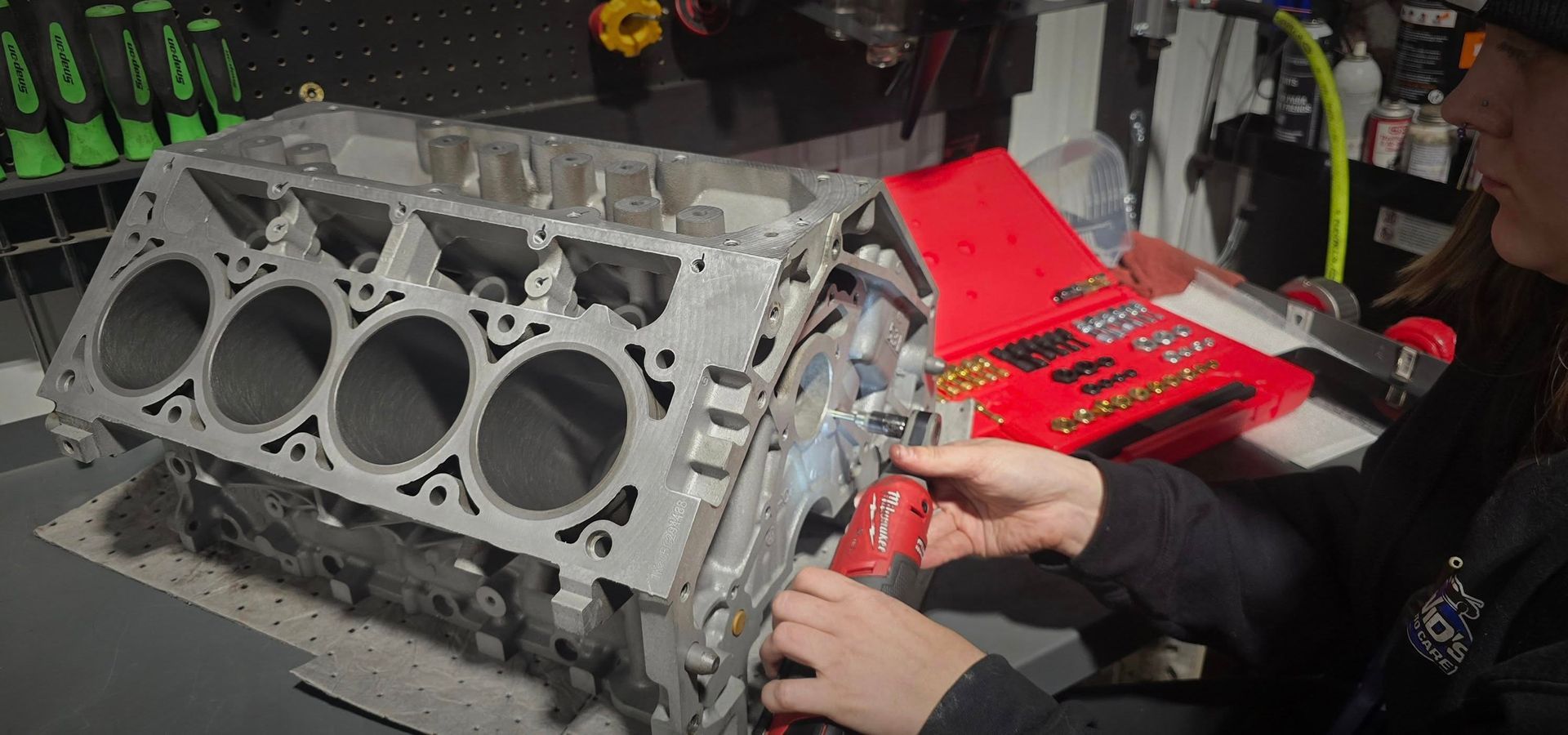 Mechanic using a red power tool on an engine block in a workshop