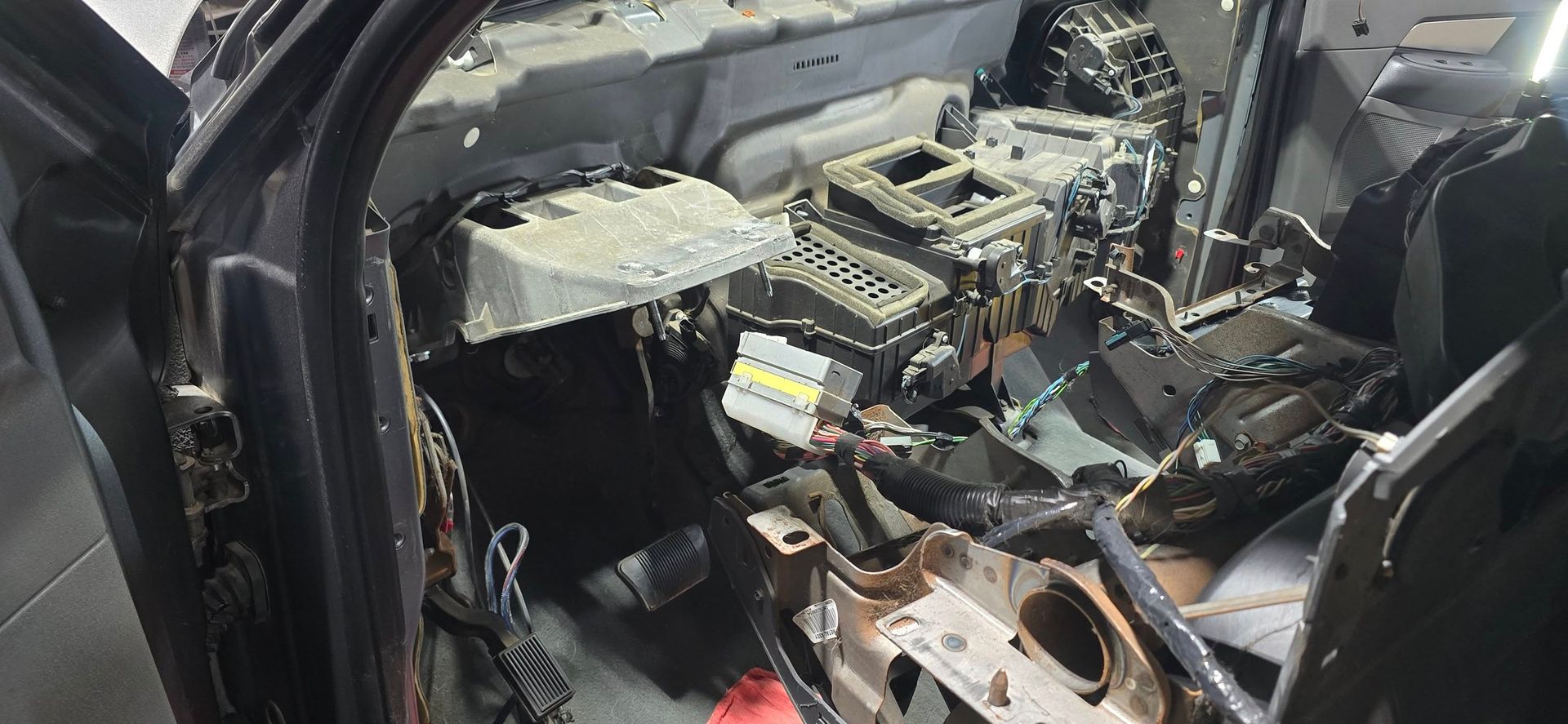 Severely damaged car interior with exposed dashboard, torn seats, and debris after a crash