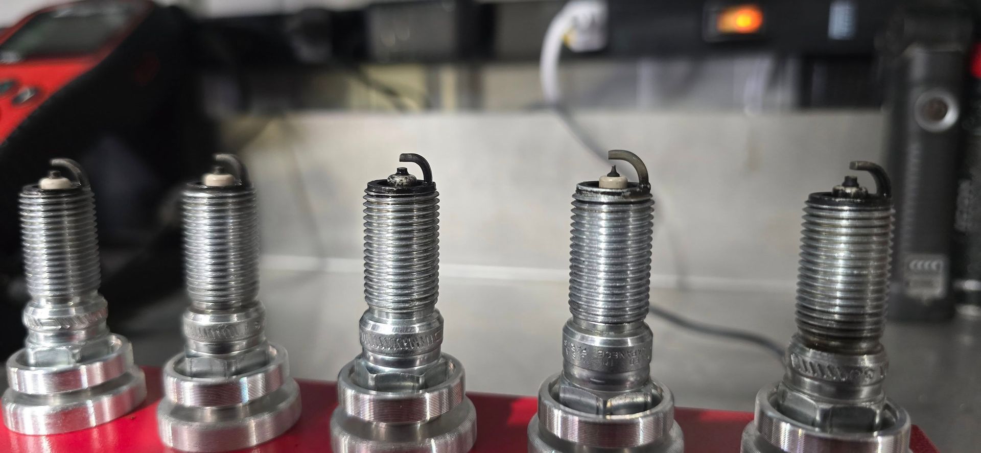 Close-up of threaded metal bolts mounted in red housings on a machine surface