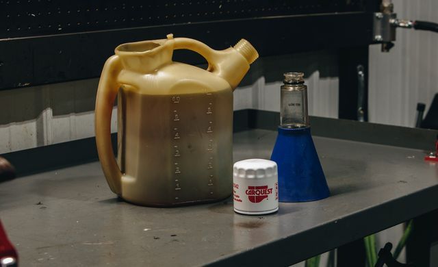 Metal pitcher, blue flask, and a white mug on a workbench in a lab or workshop setting