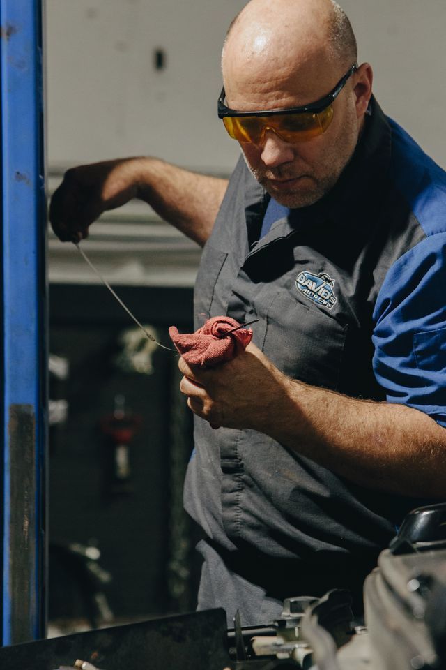 Man wearing safety glasses and gloves grilling meat over an outdoor barbecue grill