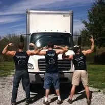 Three men stand in front of a moving truck, flexing their arms.