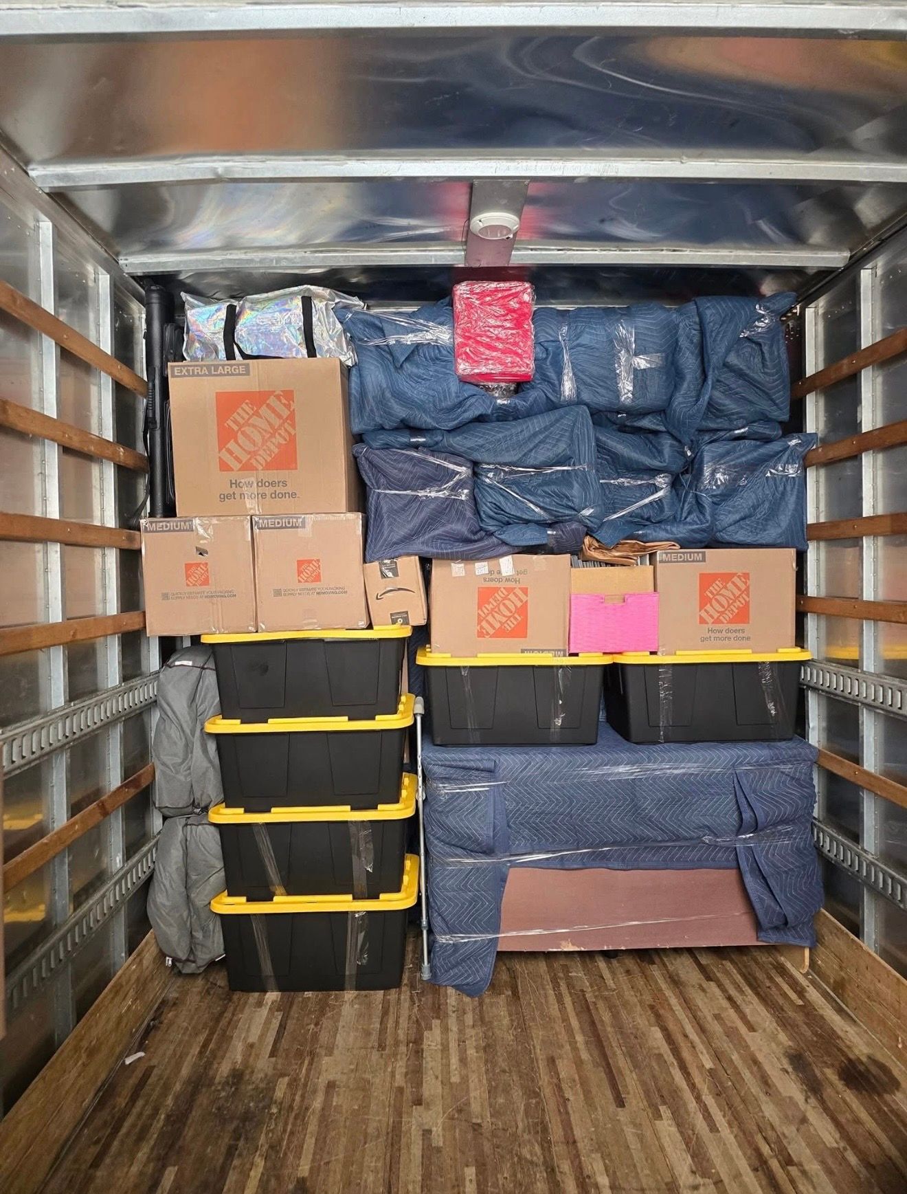 Interior of a moving truck packed with boxes, bins, and furniture.