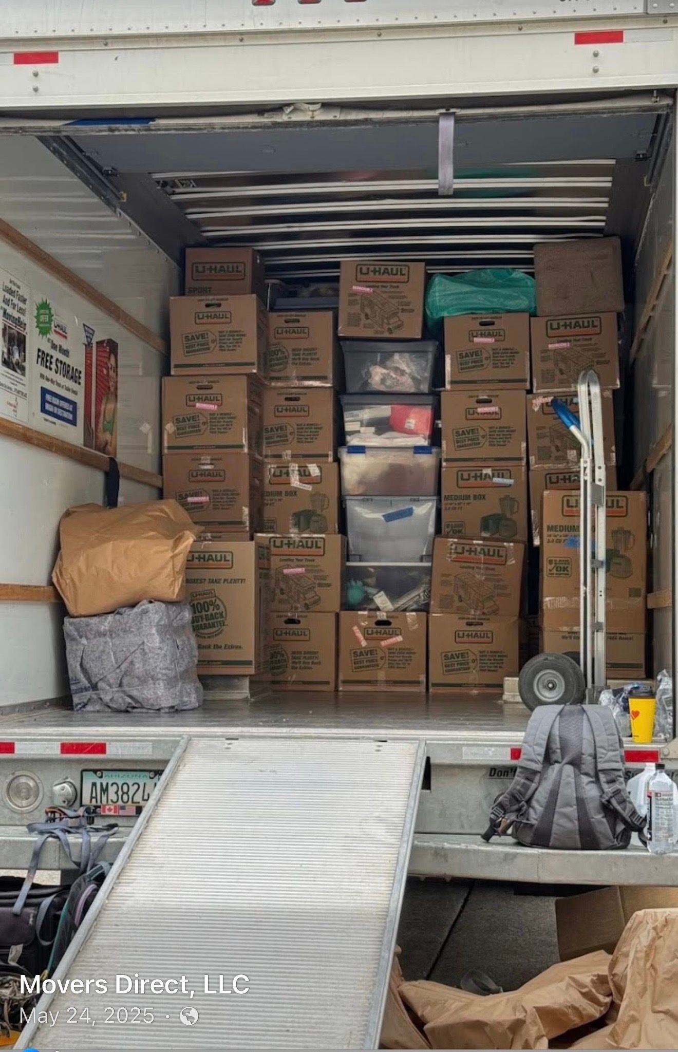 Boxes and bins stacked inside a moving truck, ramp down.