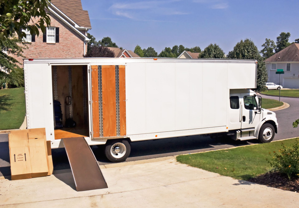 Three people giving thumbs up near a moving truck filled with boxes and luggage.