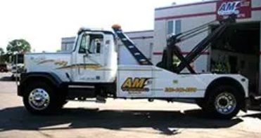 White tow truck with black boom parked outside a building,