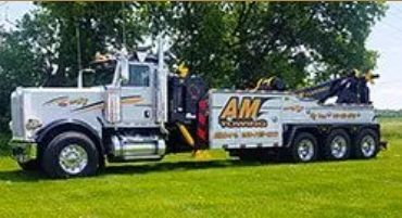 Silver AM Towing truck on green grass.