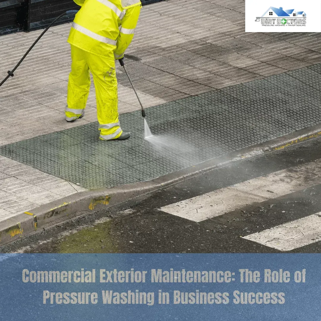 Worker in bright yellow gear pressure-washing a sidewalk curb beside a street