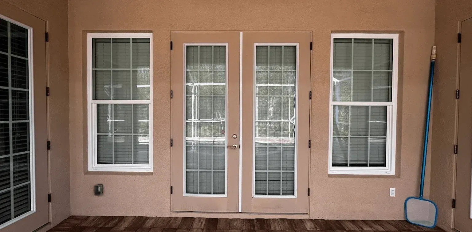 Front porch with white double glass doors and sidelights on a beige stucco wall.