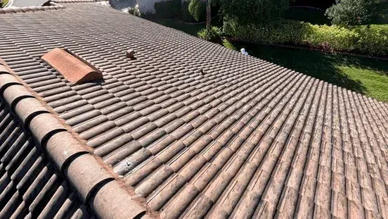 Tiled rooftop with a skylight and a vent under bright sunlight, viewed from above