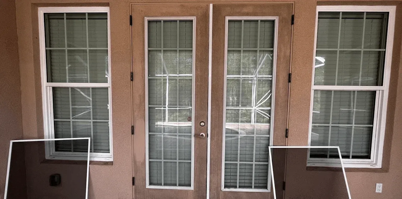Brown double doors with glass panes and two side windows, each with black mail slots or drop boxes