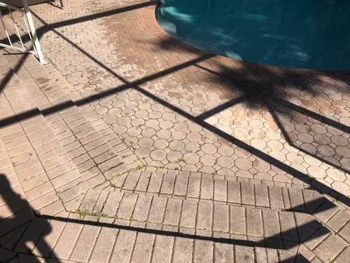 Sunlit tiled patio beside a blue pool, with diagonal shadows across the ground.
