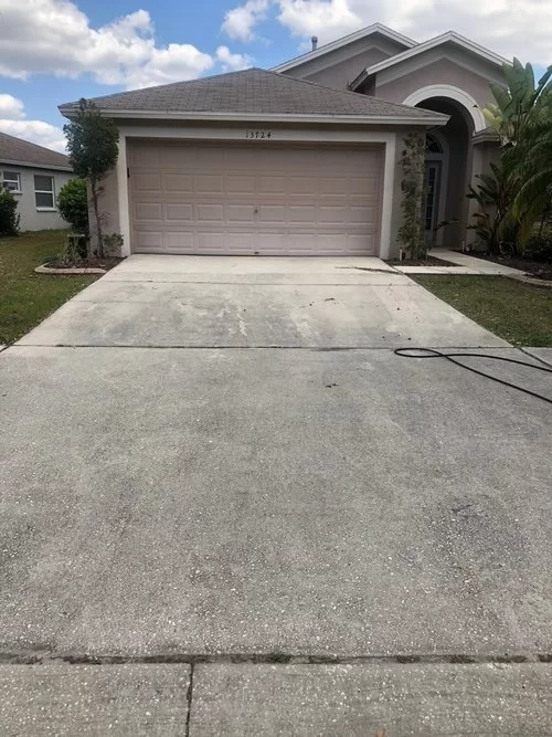 Suburban house with a two-car garage and a concrete driveway under a partly cloudy sky