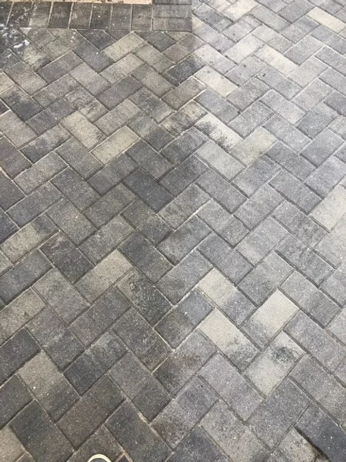 Gray and tan herringbone brick pavement with a few dark stains