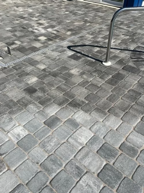 Gray cobblestone pavement with part of a metal railing or stand on the right.