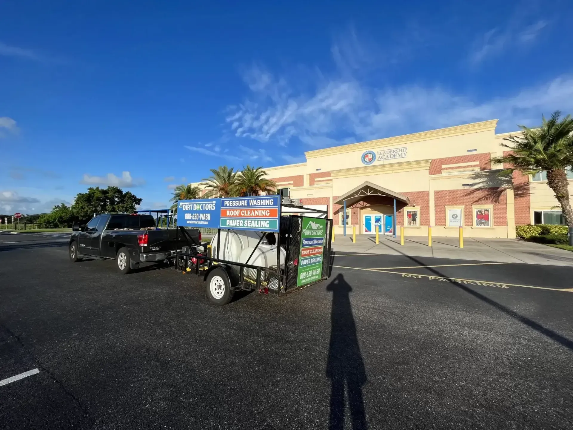 Shopping carts and parked cars outside a storefront on a sunny day under a blue sky.