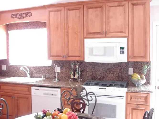 Kitchen with light wood cabinets, granite countertops, and white appliances.