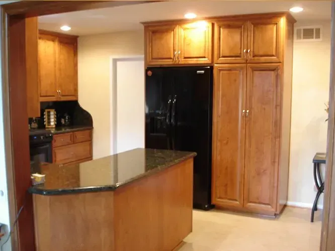 Kitchen with wood cabinets, black refrigerator, granite countertops, and an island.