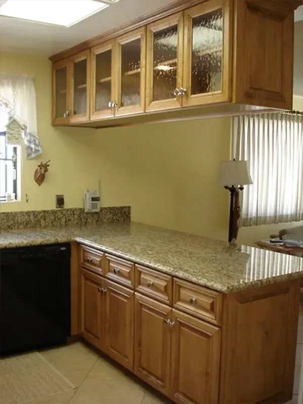 Kitchen with wooden cabinets, granite countertops, and black dishwasher.
