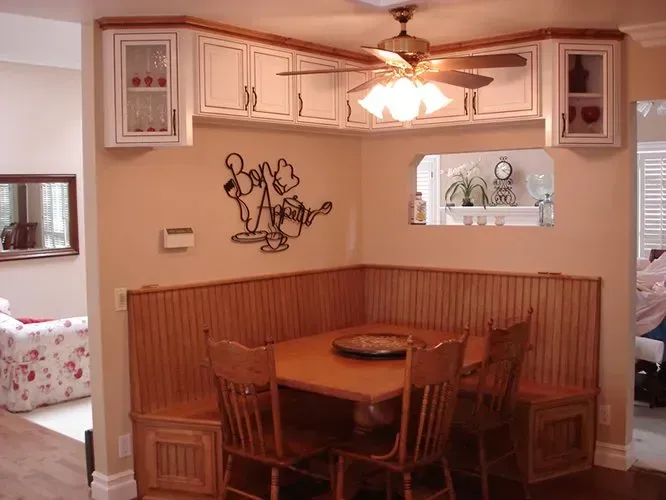 Dining area with wooden booth seating and overhead cabinets. Table and chairs in a nook with Winnie the Pooh silhouette.