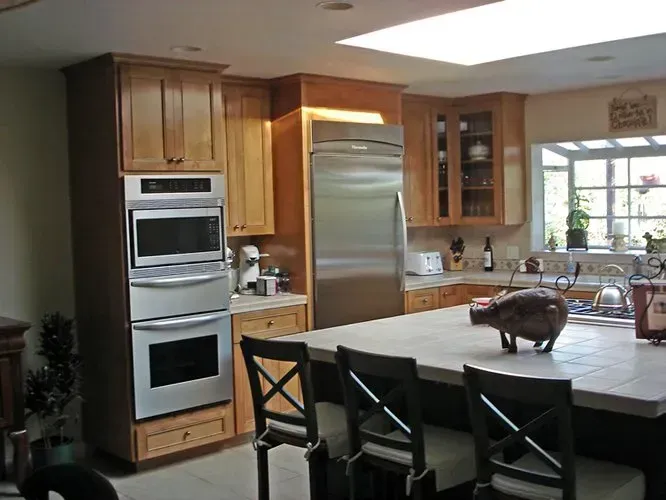Kitchen with light wood cabinets, stainless steel appliances, and a large island with seating.