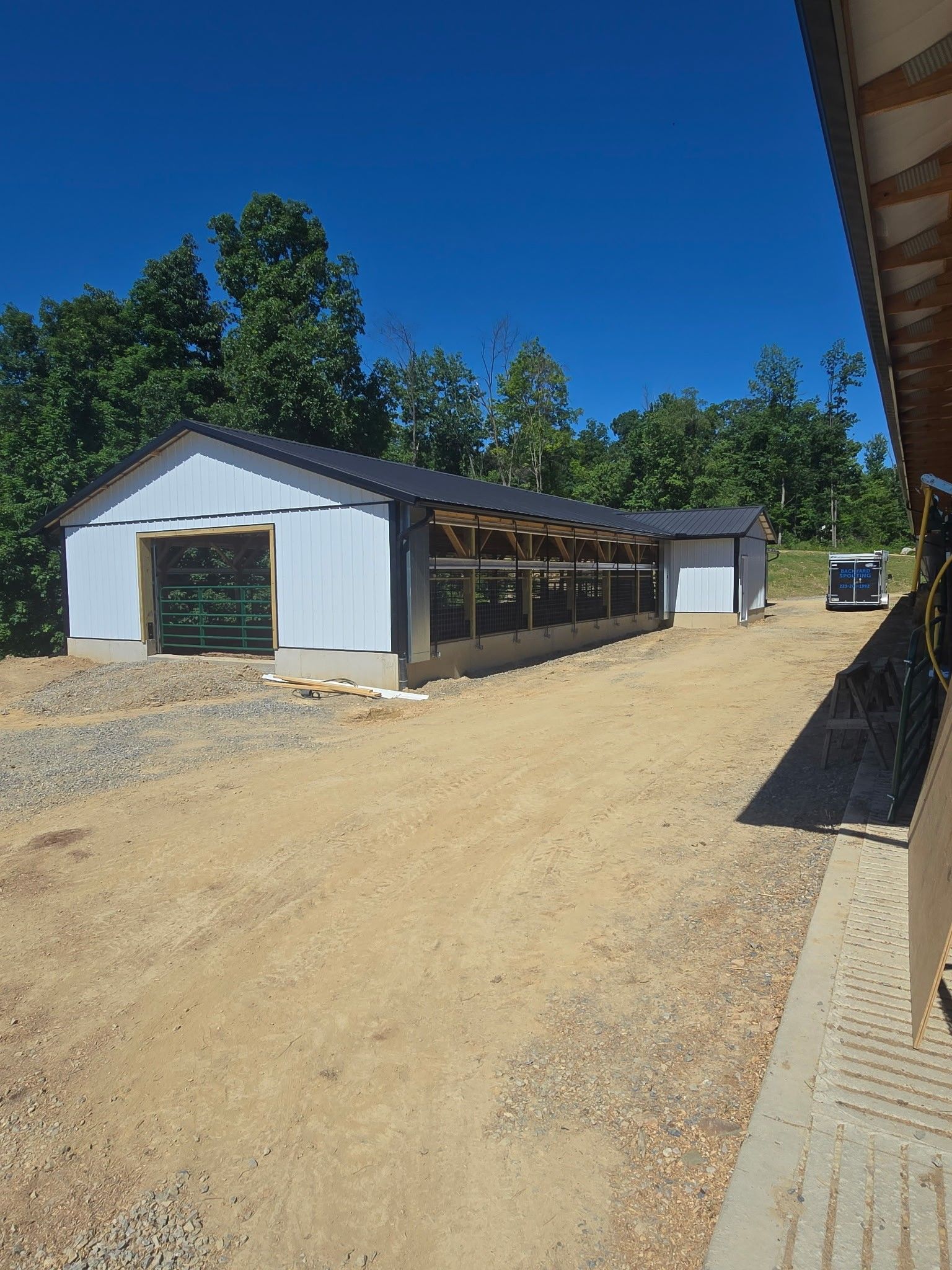 White industrial building with a long covered side walkway on a dirt lot under a clear blue sky