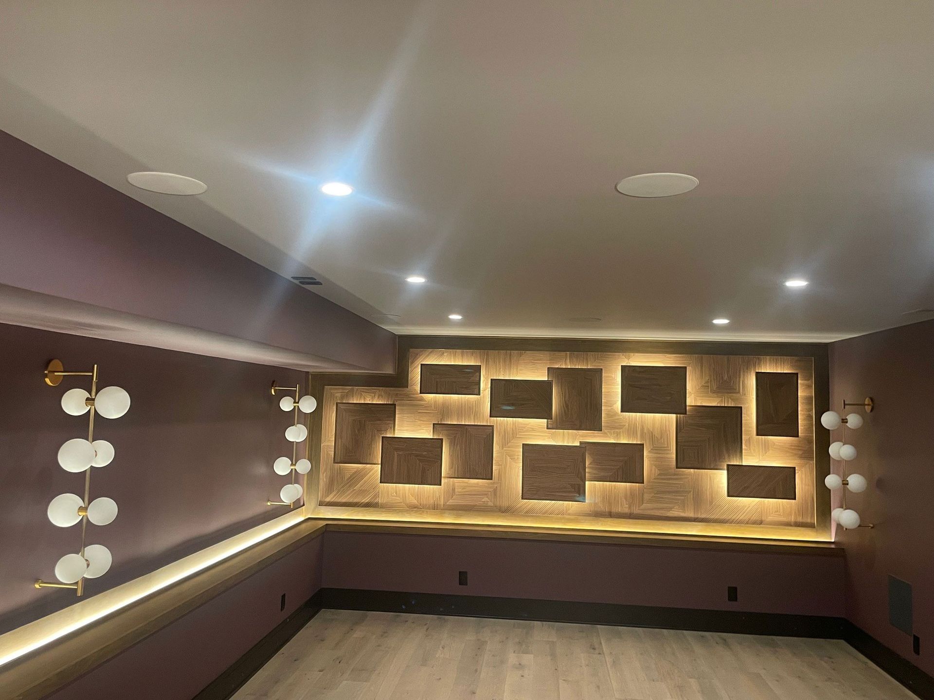 A room with pink walls, a stage, decorative wall, and recessed lighting.