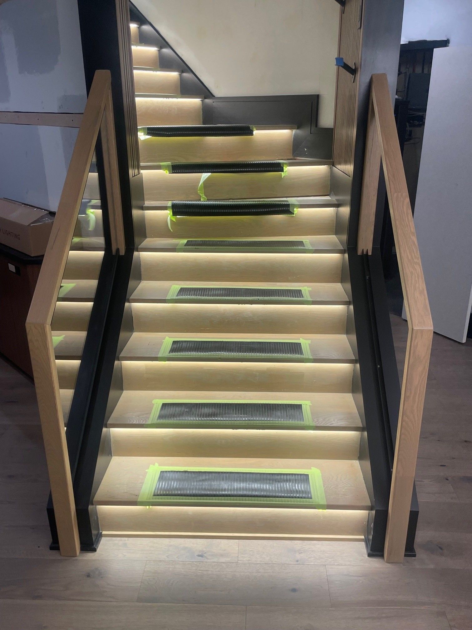 Modern staircase with wood and black accents, lit steps.