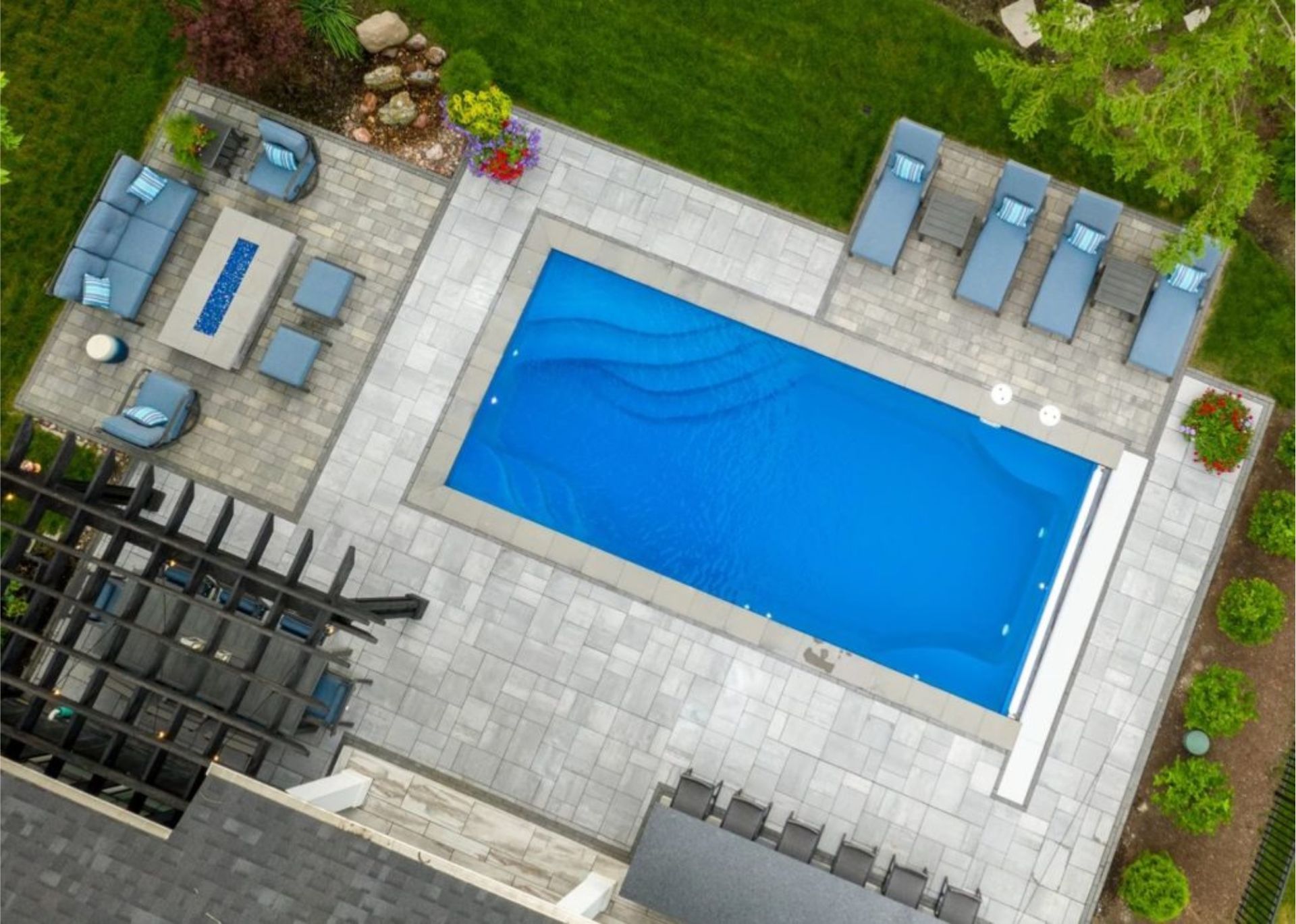 an aerial view of a backyard with a large swimming pool and patio furniture