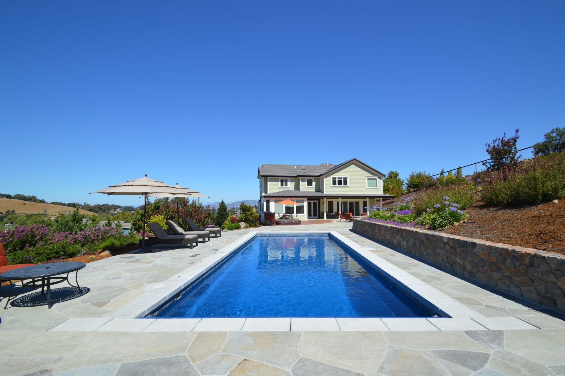 a large swimming pool with a house in the background