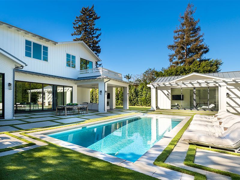 a large white house with a large swimming pool in the backyard