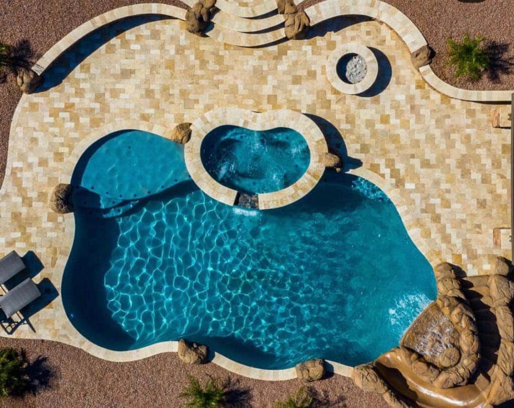 an aerial view of a large swimming pool with a hot tub in the middle