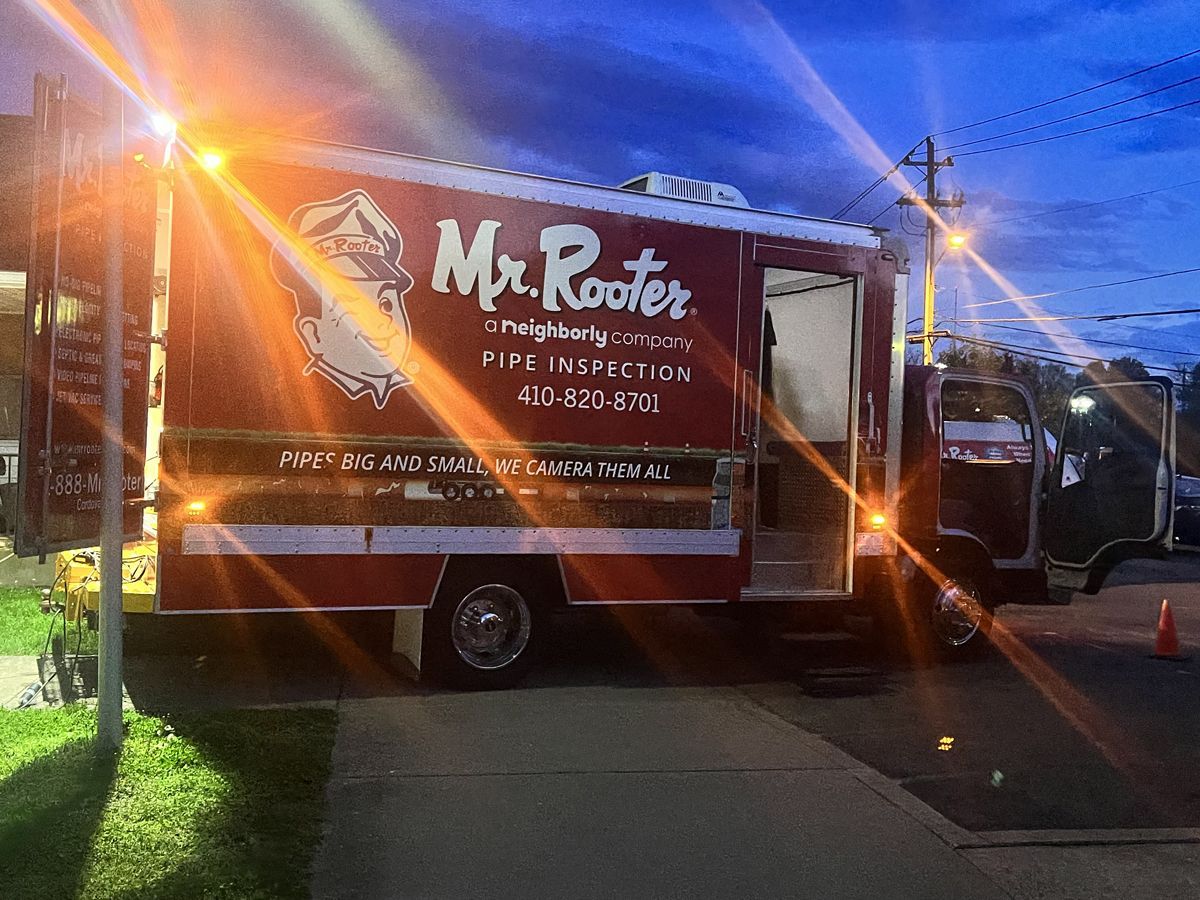 Branded food truck parked at dusk, with orange flare and traffic cones on the roadside.