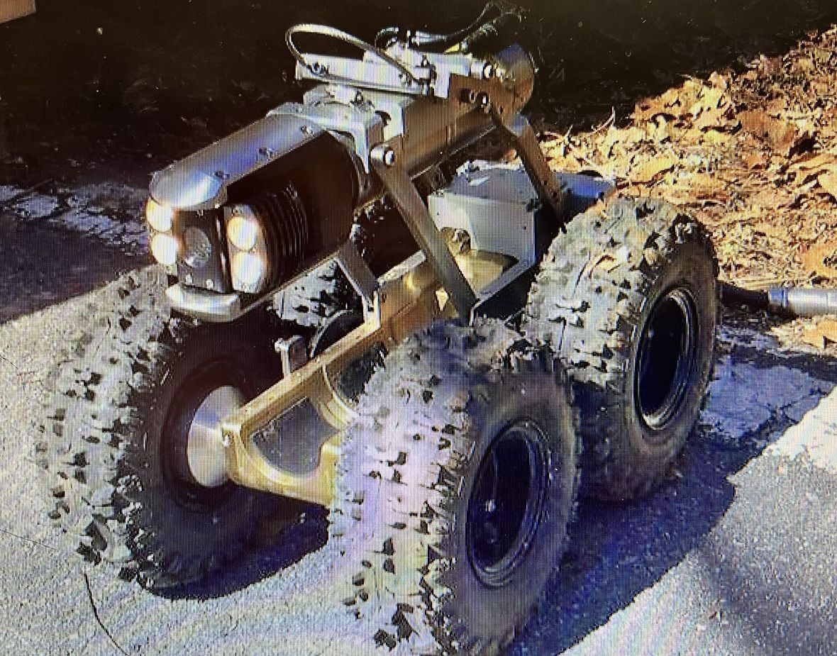 Small muddy off-road vehicle with oversized tires parked on pavement at night.