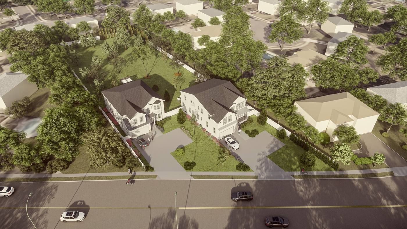 Aerial view of suburban houses with tree-lined yards beside a road with passing cars.