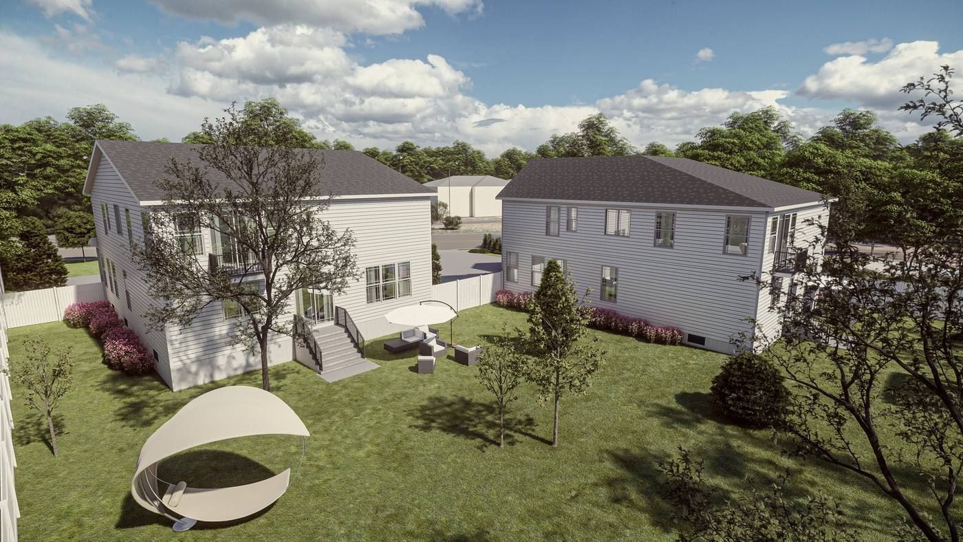 Two white houses with gray roofs and a green yard, viewed from above on a sunny day