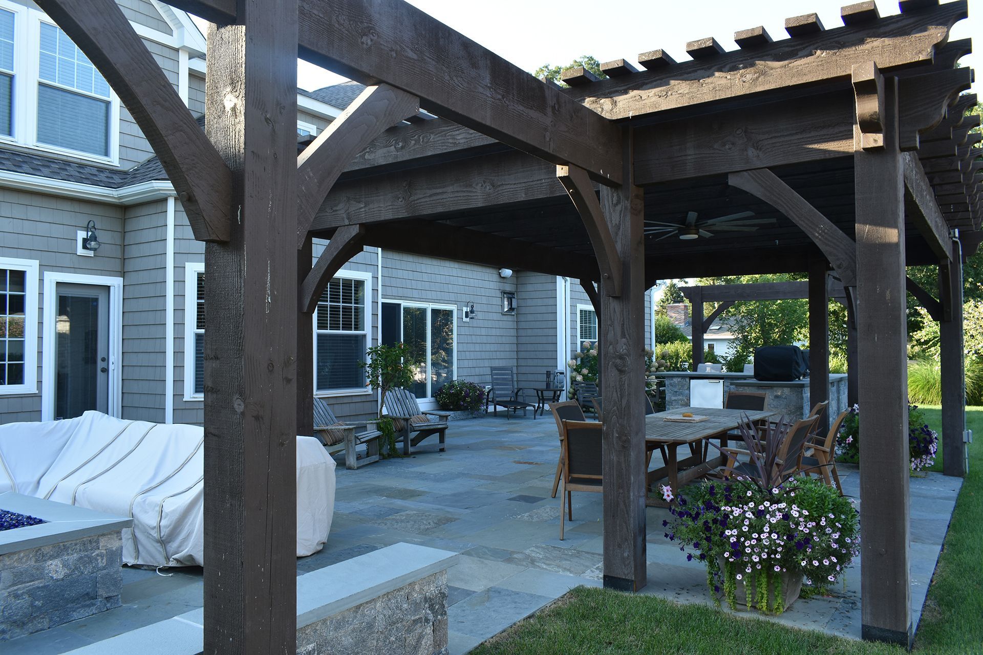 A wooden pergola with a table and chairs underneath it