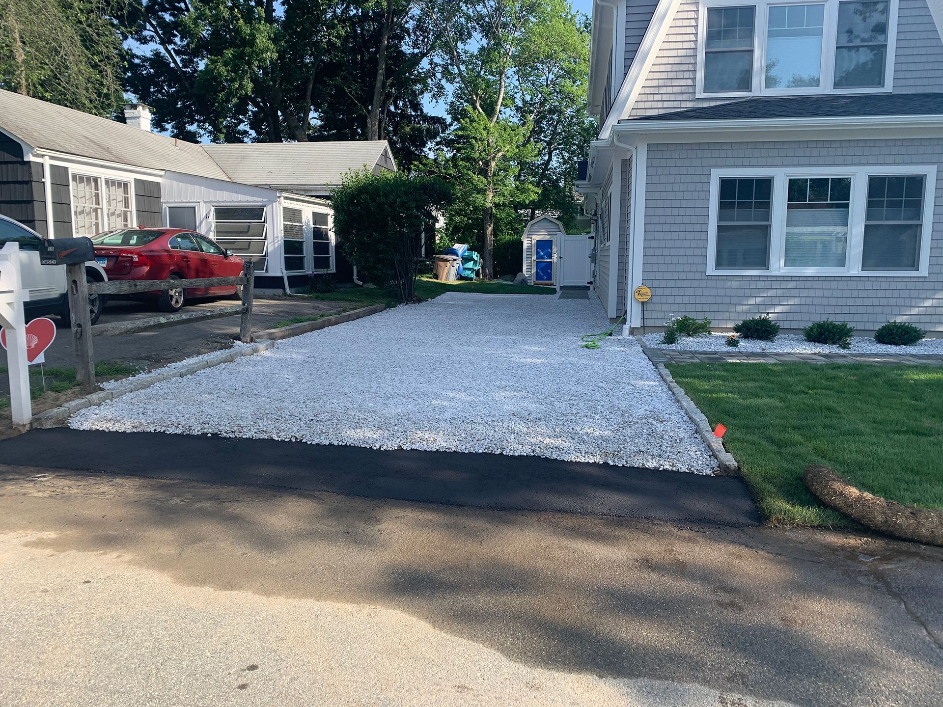 A driveway with gravel and a car parked in front of a house.
