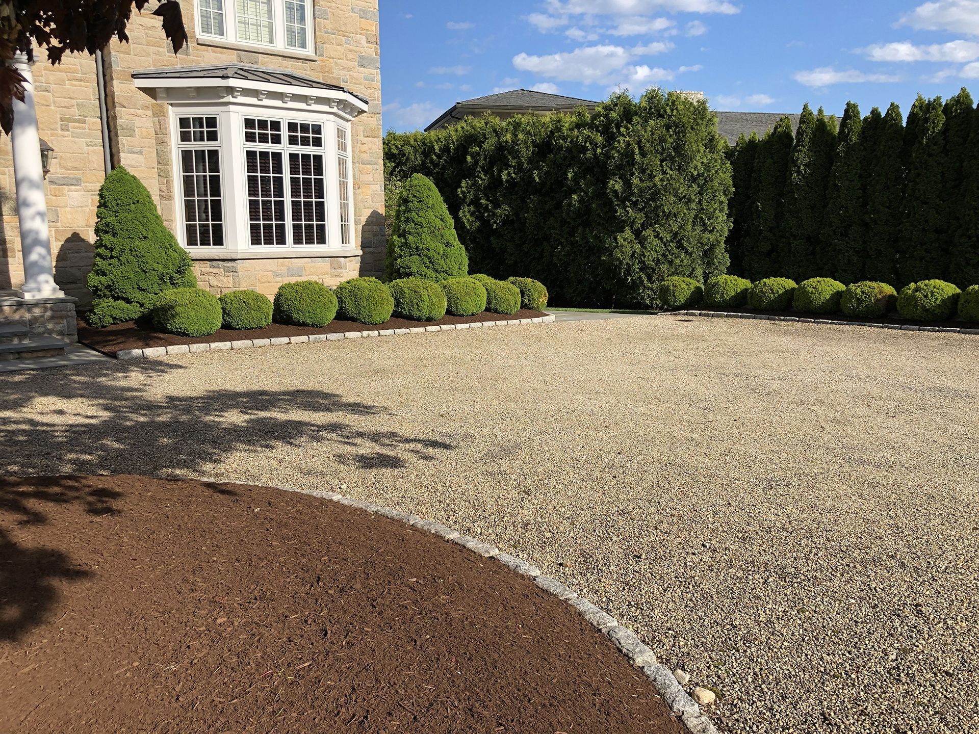 A large house with a gravel driveway in front of it.