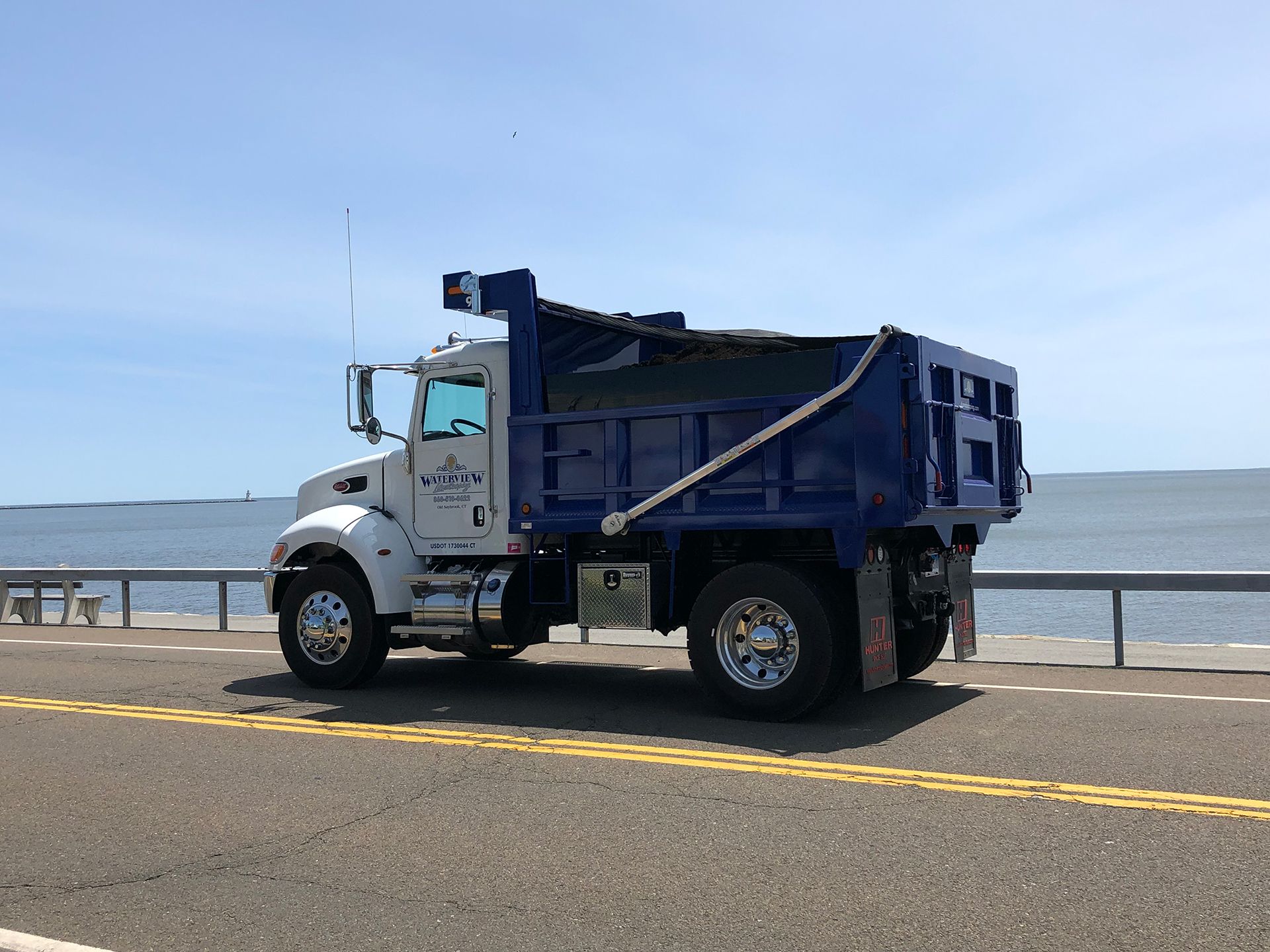 A dump truck is parked on the side of the road near the ocean.