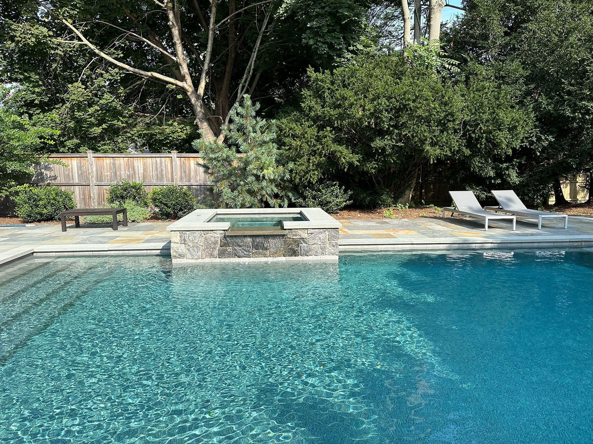 A large swimming pool surrounded by trees and chairs.
