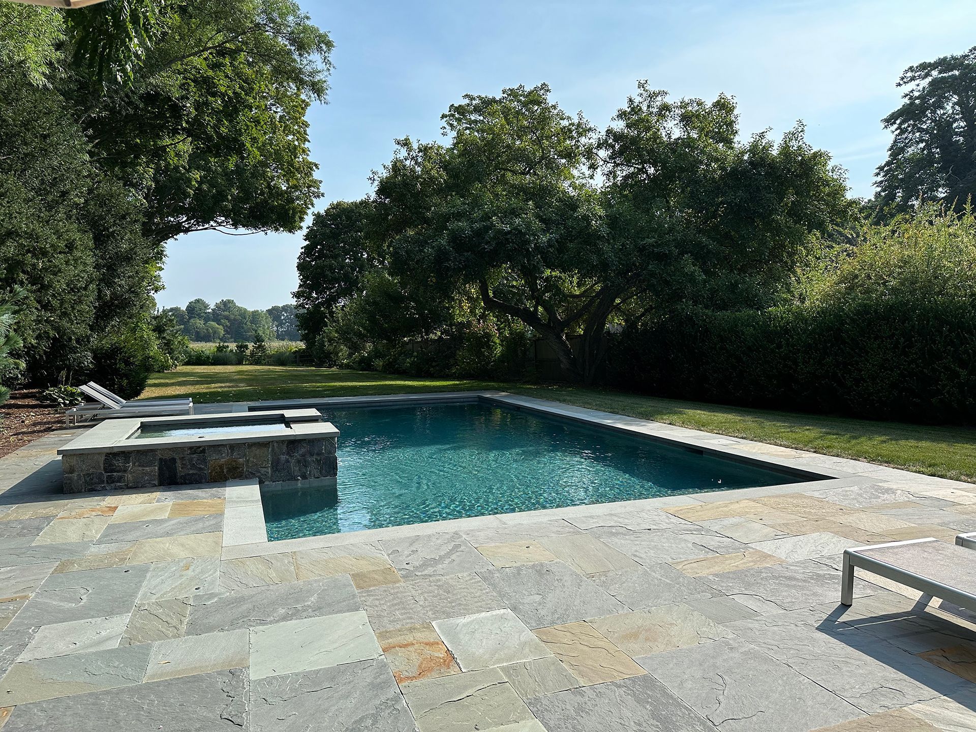 A large swimming pool surrounded by trees on a sunny day