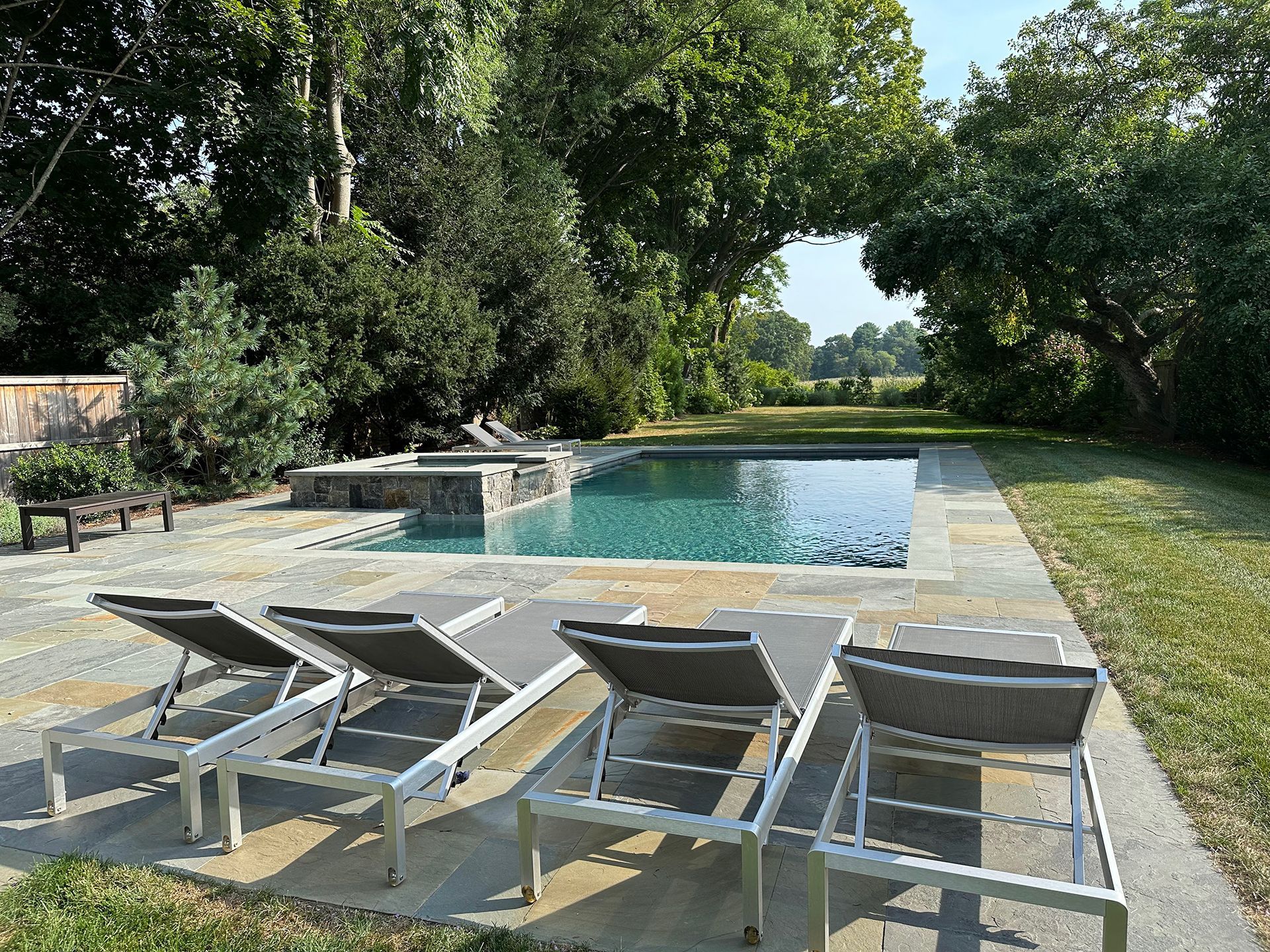 A swimming pool surrounded by lawn chairs and trees