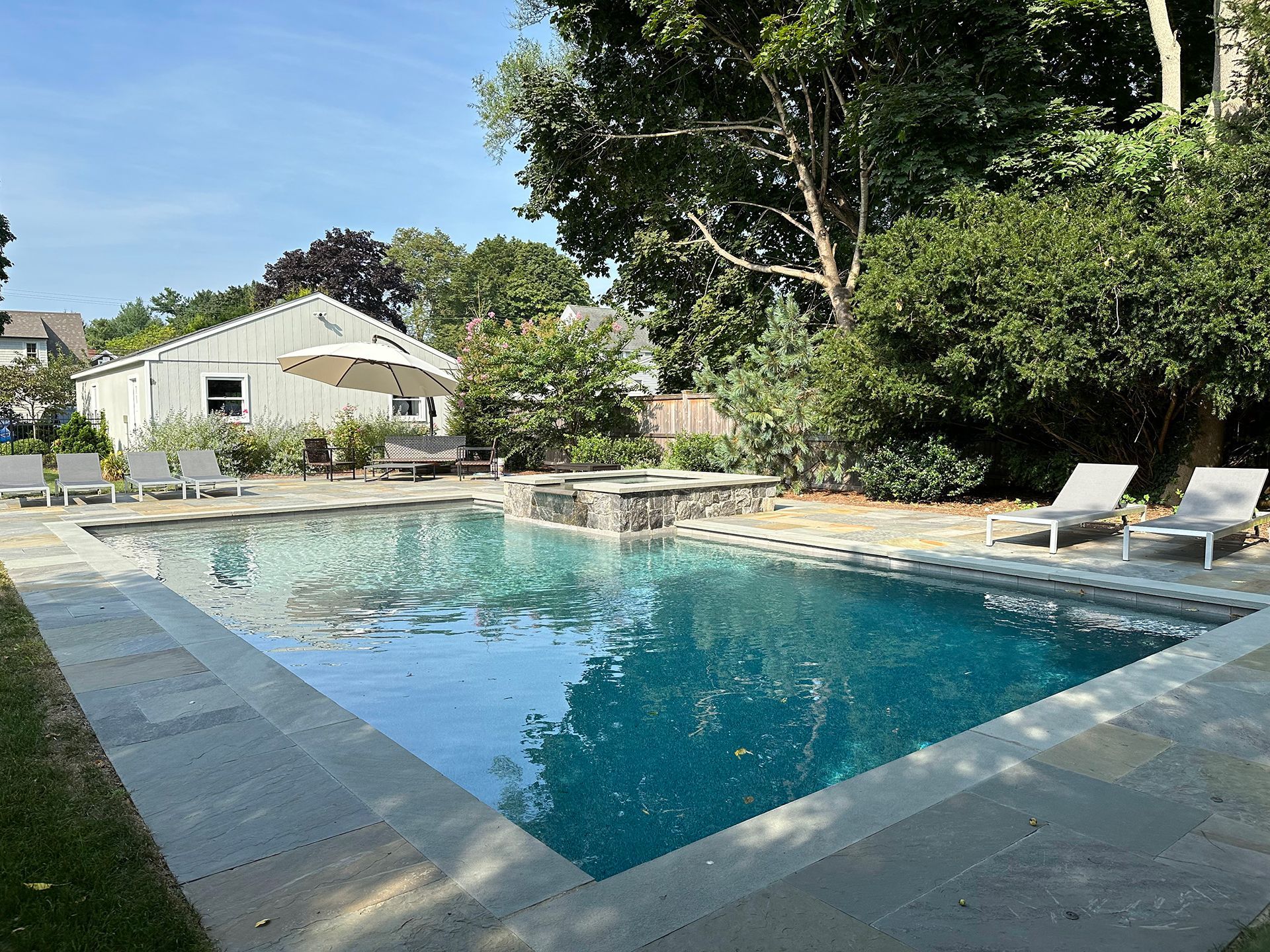 A large swimming pool surrounded by chairs and trees