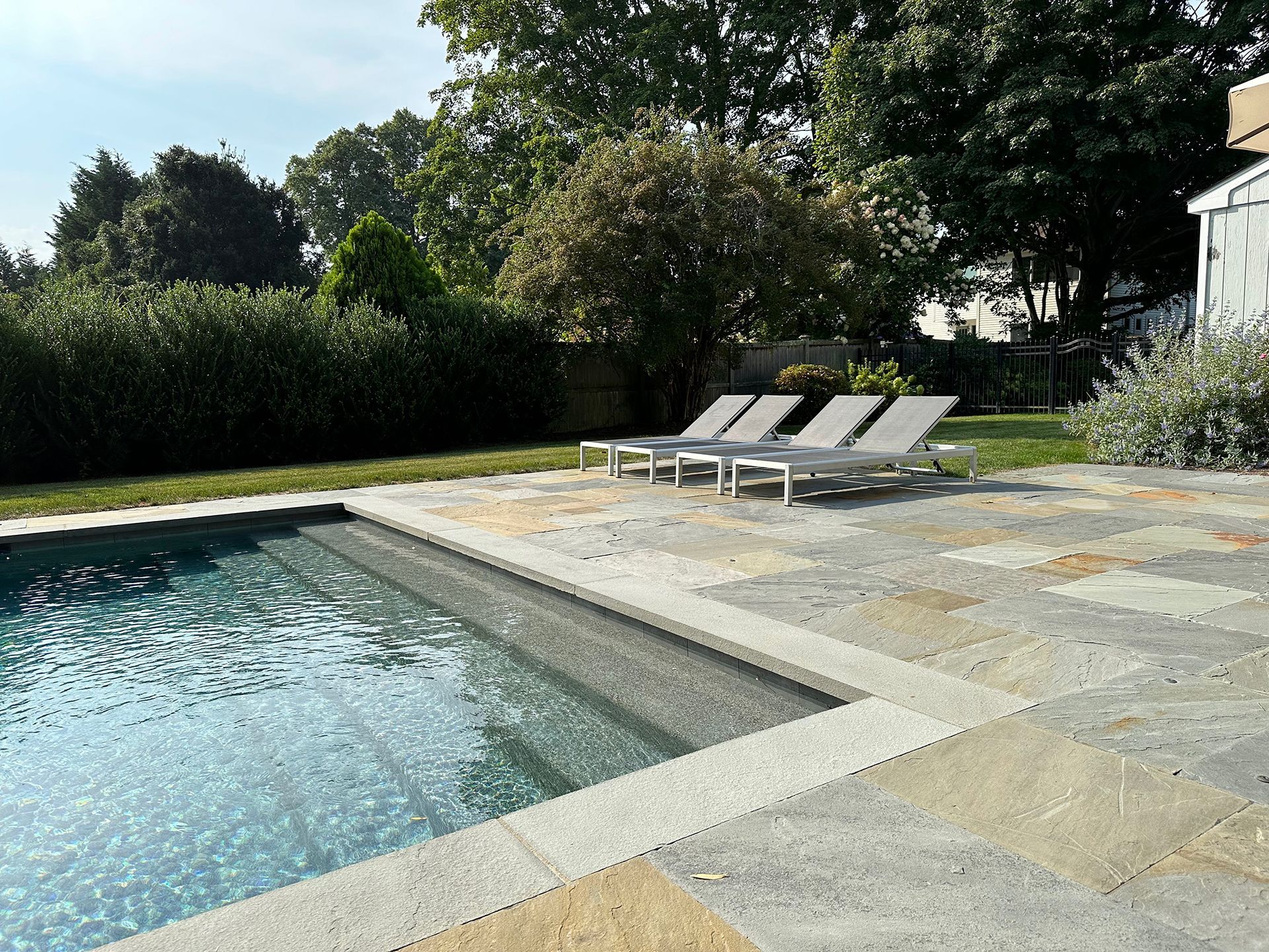 A swimming pool with a patio and chairs around it