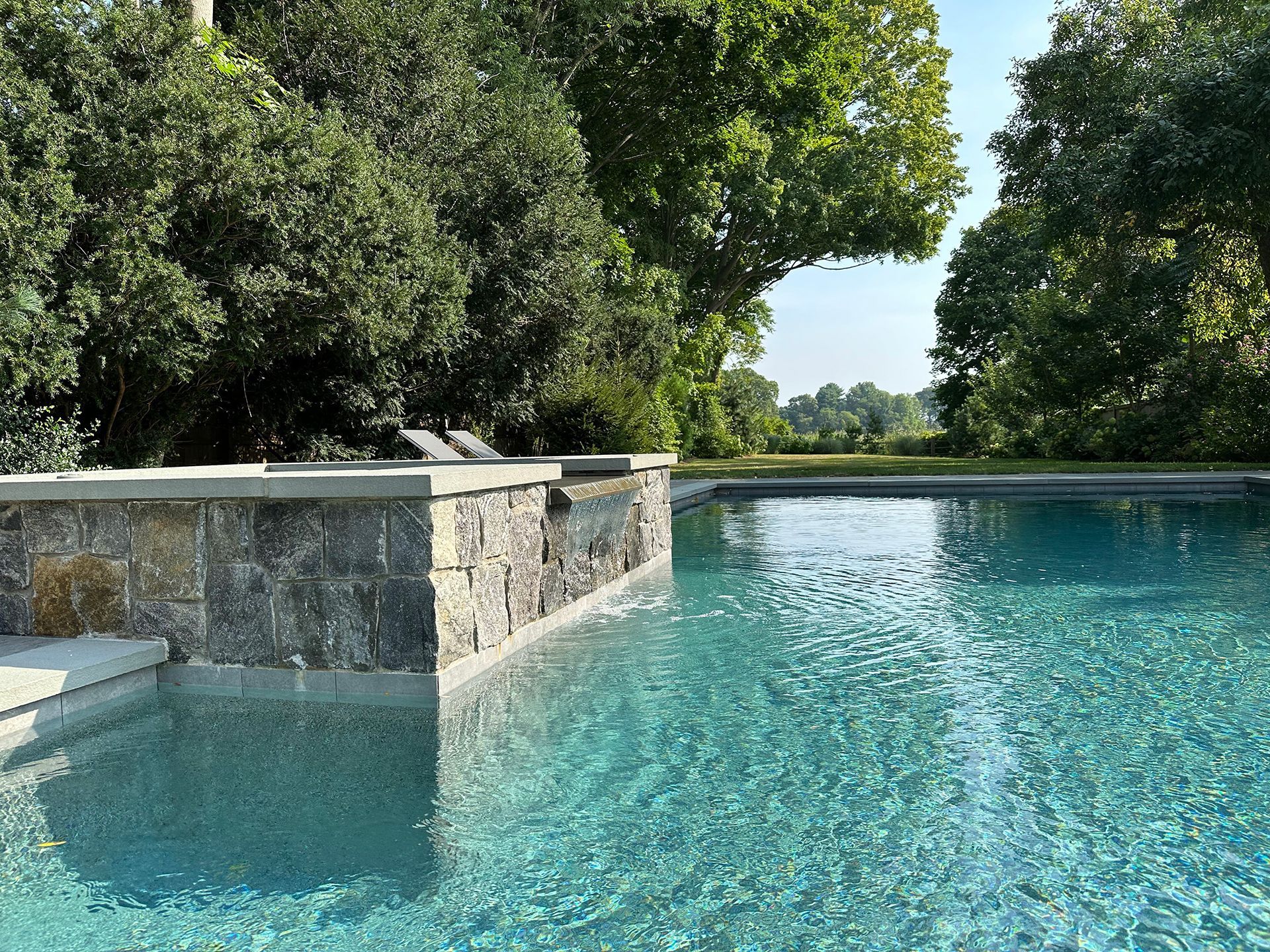 A large swimming pool surrounded by trees on a sunny day