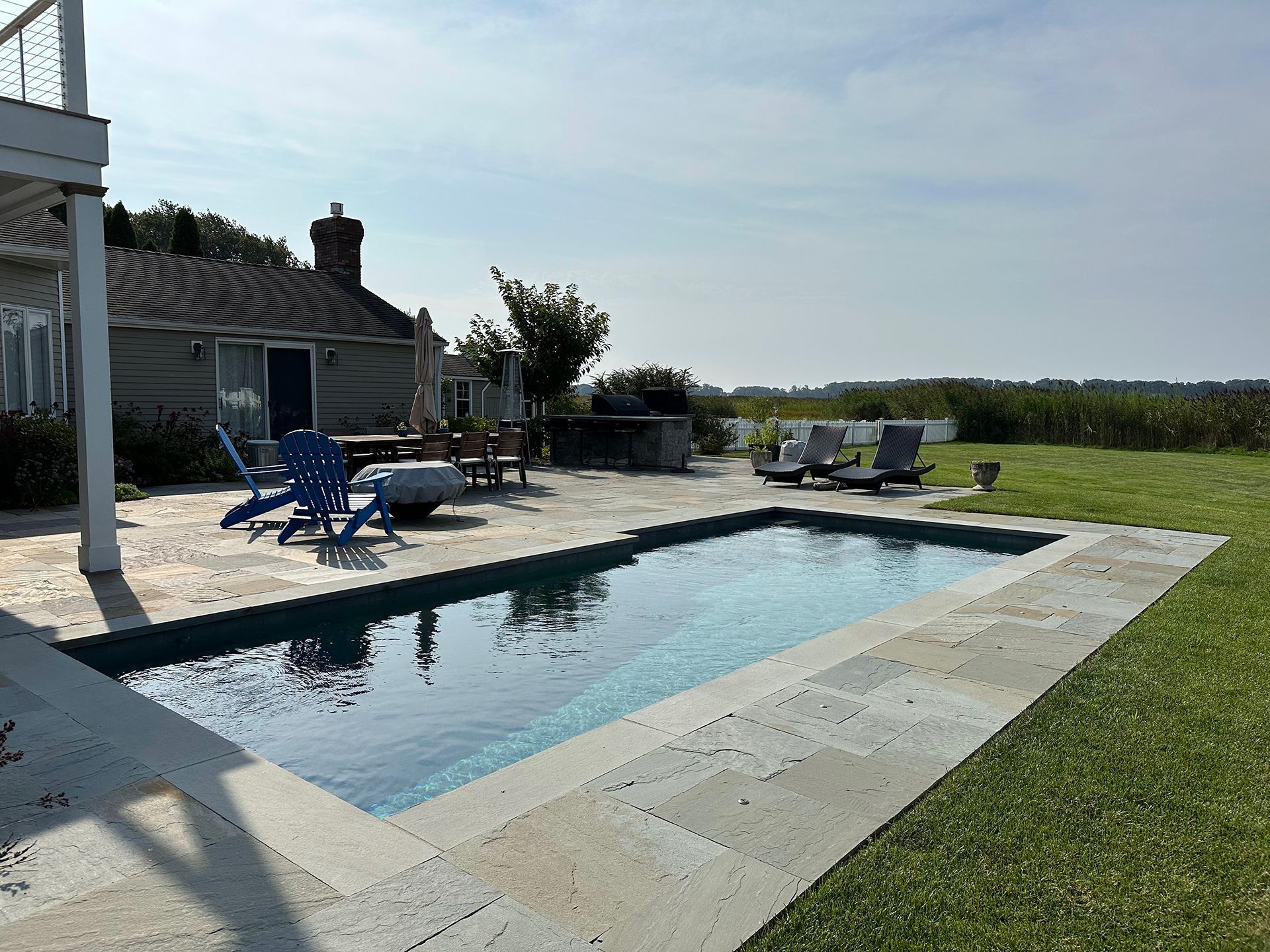 A large swimming pool is in the backyard of a house.